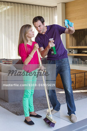 Father and daughter holding cleaning equipment and discussing