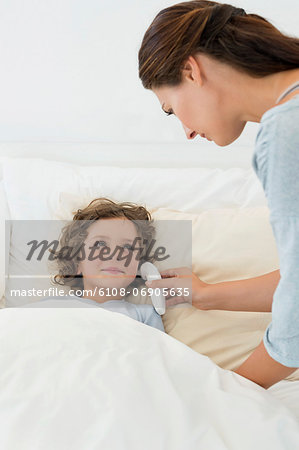 Woman checking fever of her son with a thermometer