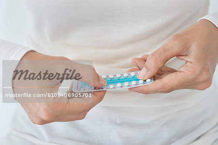 Mid section view of a woman holding a blister pack of contraceptive pills
