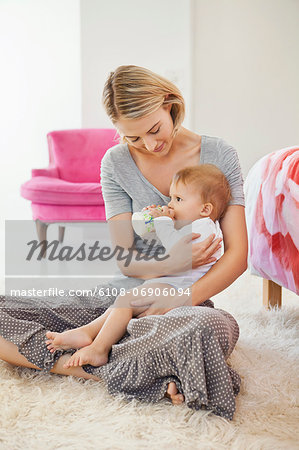 Woman sitting with her baby feeding with a baby bottle