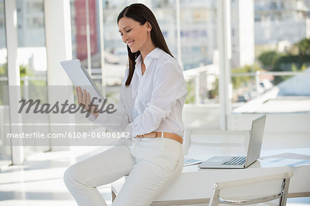 Businesswoman holding a digital tablet and smiling in an office