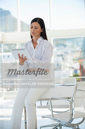 Businesswoman using a digital tablet while sitting on a table in an office