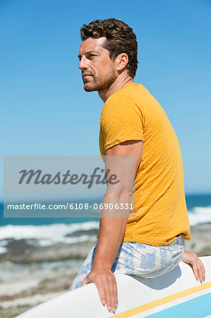 Man sitting on a surfboard on the beach