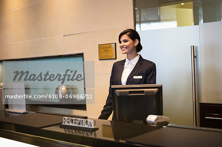 Receptionist standing at the hotel reception counter and smiling