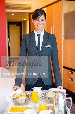 Portrait of waitress smiling with room service table in a hotel room