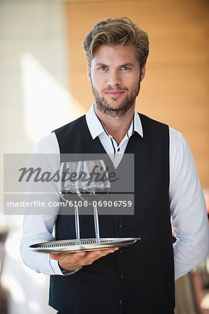 Portrait of a waiter holding a tray of wine glasses in a restaurant