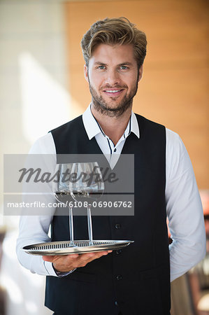 Portrait of a waiter holding a tray of wine glasses in a restaurant