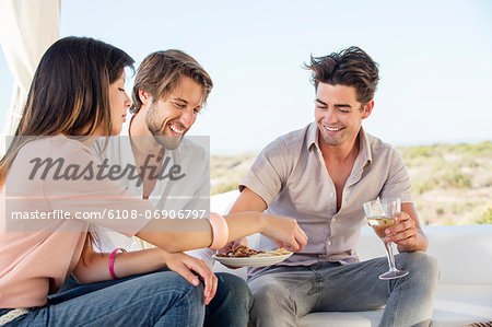 Three friends enjoying snacks and drinks in outdoor