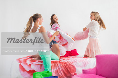 Girls having pillow fight on the bed at a slumber party