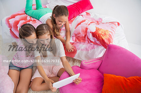 Three girls using a digital tablet at a slumber party