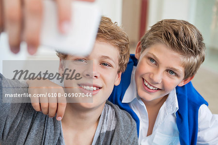 Two teenage boys taking a picture of themselves with a mobile phone