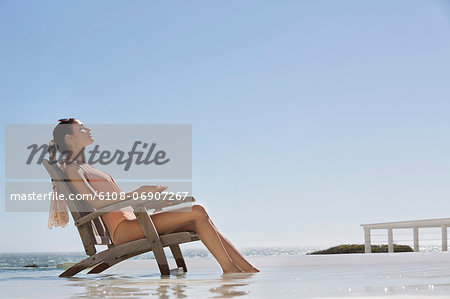 Beautiful woman sitting on a chair on the beach