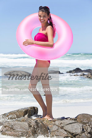 Beautiful woman standing with an inflatable ring on the beach