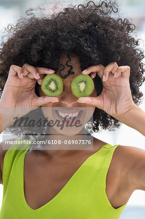 Woman holding kiwi fruits in front of her eyes
