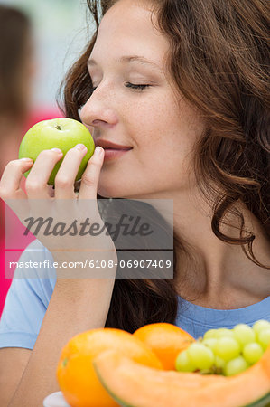 Close-up of a woman smelling a green apple