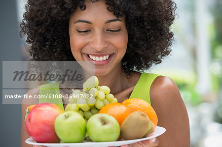 Smiling woman holding a plate of fruits