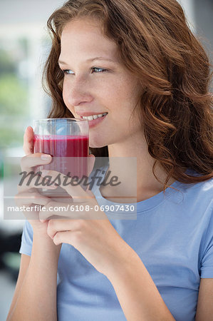 Smiling woman holding a glass of pomegranate juice