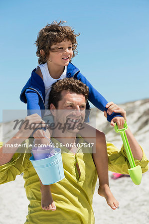 Man carrying his son on shoulders on the beach