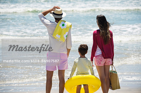 Boy with his parents looking at sea on the beach