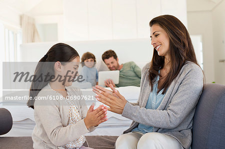 Mother and her daughter playing Pat-a-cake and smiling