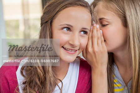 Close-up of two girls whispering in a school