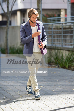 Man walking on a street reading text message