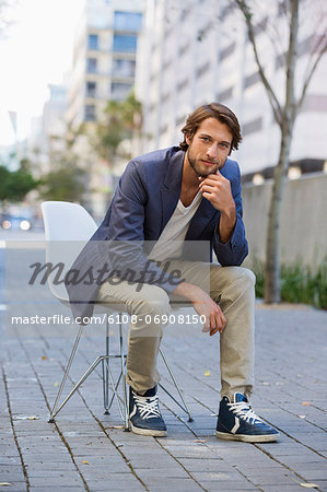 Portrait of a man sitting on a chair on a street