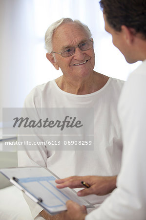 Doctor talking with older patient in hospital room