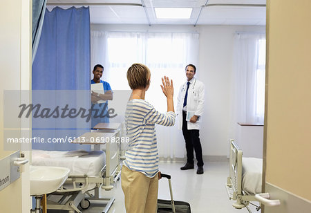 Patient waving to doctor in hospital room Patient waving to doctor in hospital room