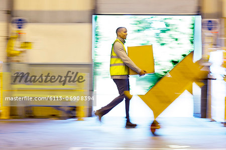 Blurred view of workers carrying boxes in warehouse