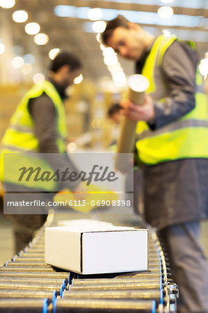 Workers checking packages on conveyor belt in warehouse