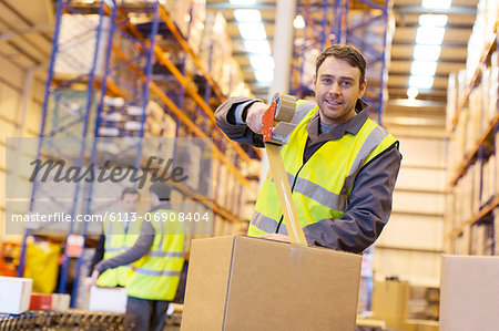 Worker taping cardboard box in warehouse