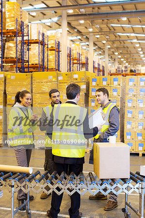 Businessman and workers talking in warehouse