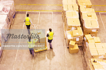 Workers carting boxes in warehouse