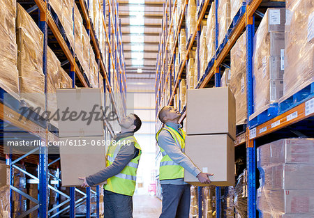Workers carrying boxes in warehouse