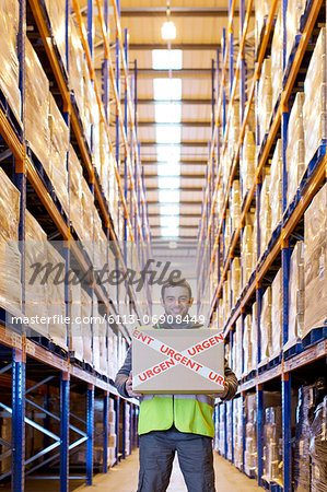 Worker carrying "urgent" box in warehouse