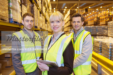 Businesswoman and workers smiling in warehouse