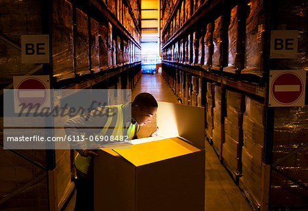 Worker opening glowing box in warehouse