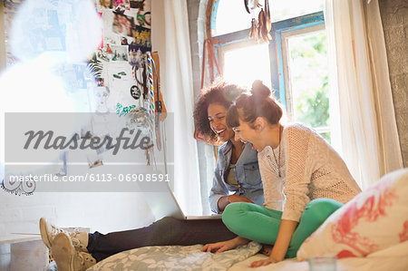 Women using laptop together in bedroom