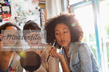 Women applying makeup in bedroom Women applying makeup in bedroom