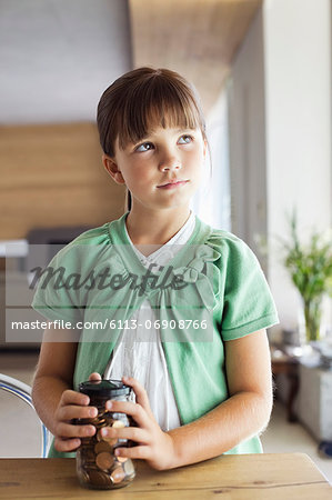 Girl holding change jar at table