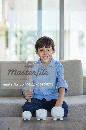 Boy holding hammer to smash piggy banks