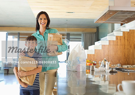 Mother and son holding groceries in kitchen