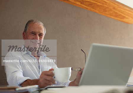 Older man having cup of coffee at desk