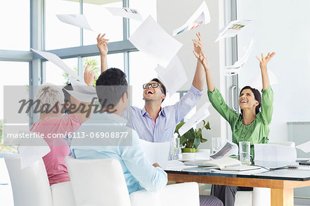 Business people tossing papers in air in meeting