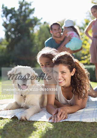 Mother, daughter and dog laying in grass
