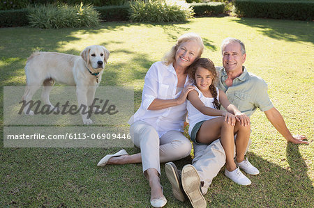 Older couple smiling with granddaughter in backyard