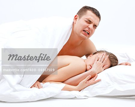 Young, naked couple in bed, the man leaning over the woman