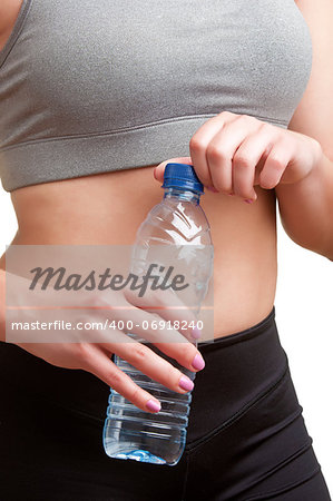 Woman holding a plastic bottle of water, dressed in sports clothes, isolated in white