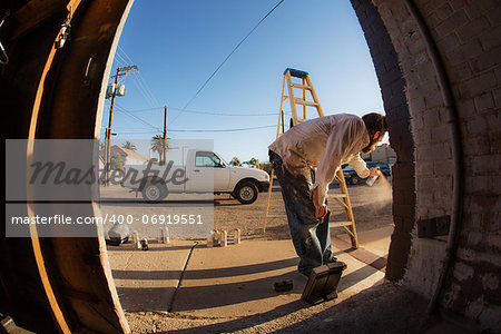 Wide angle view of man with spray paint cans and ladder